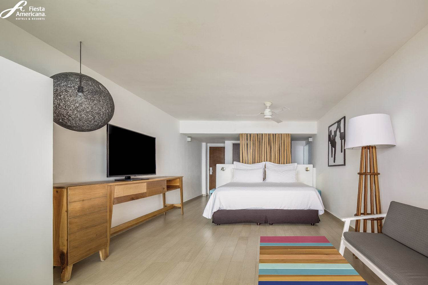 Modern hotel room with bed, TV, and decor elements.