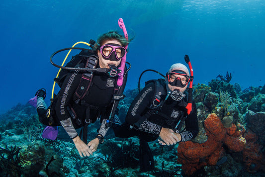 Two scuba divers exploring colorful coral reefs underwater in Cozumel Mexico